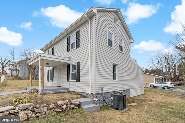 view of side of home with cooling unit, a yard, and a porch