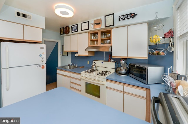 kitchen with sink, white appliances, and white cabinets