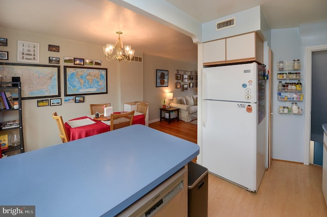 kitchen featuring white refrigerator, white cabinets, light wood-type flooring, and pendant lighting