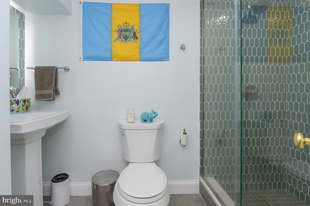 bathroom featuring a tile shower, tile patterned floors, and toilet