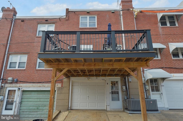 rear view of property with a garage, a balcony, and central AC