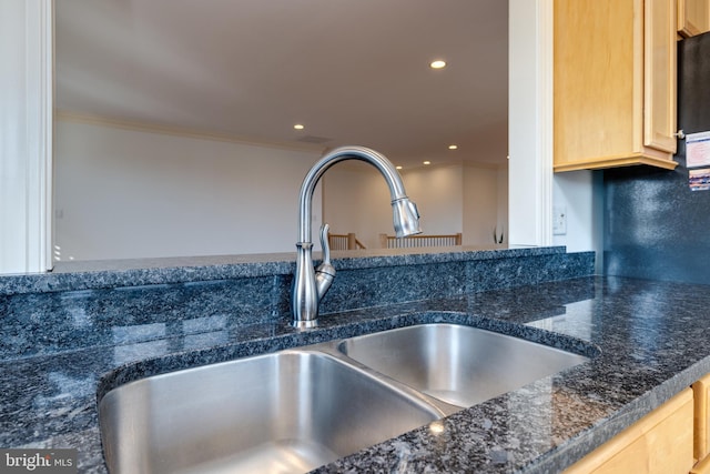 room details with crown molding, sink, light brown cabinetry, and dark stone counters