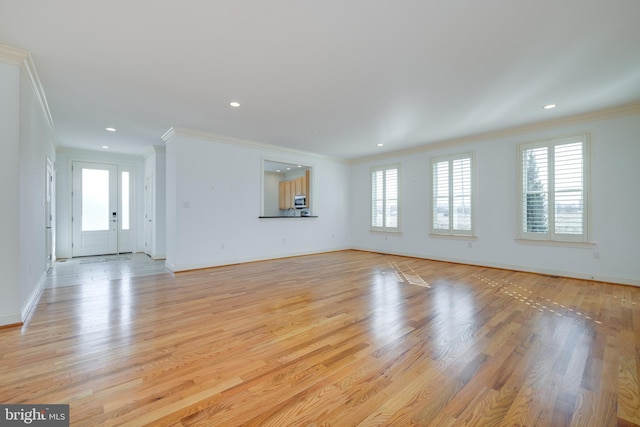 unfurnished living room featuring crown molding, plenty of natural light, and light hardwood / wood-style floors