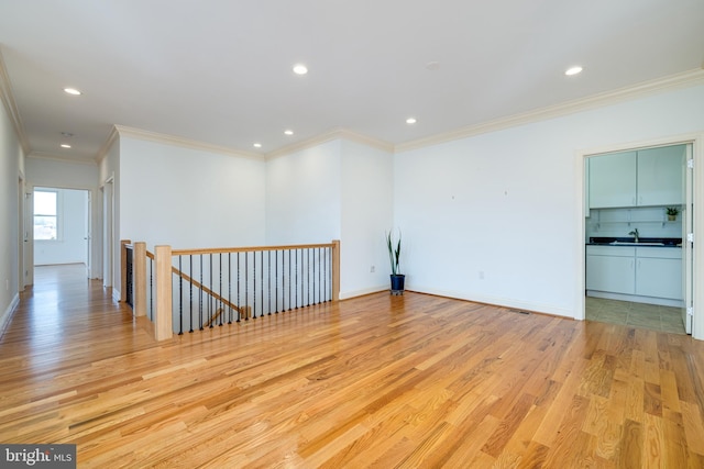 empty room featuring sink, crown molding, and light hardwood / wood-style floors