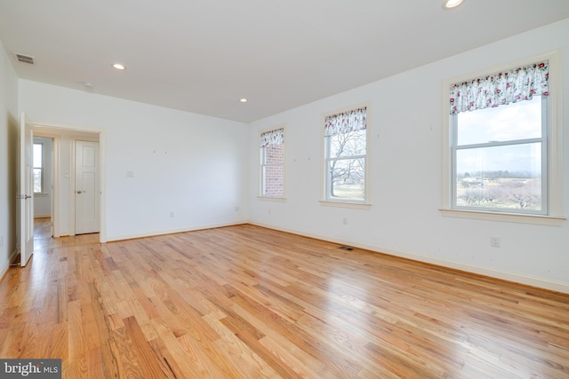 empty room with light hardwood / wood-style floors and a healthy amount of sunlight