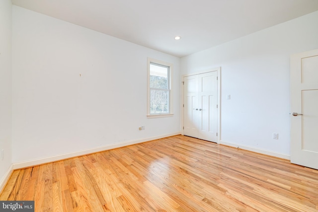 unfurnished bedroom with light wood-type flooring and a closet