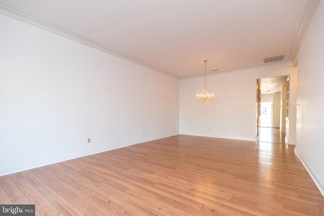 spare room with an inviting chandelier, ornamental molding, and light hardwood / wood-style floors