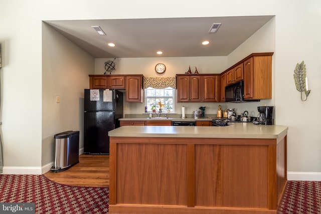 kitchen featuring dark wood-type flooring, kitchen peninsula, sink, and black appliances