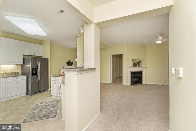 400 Symphony Cir Unit 136E, Cockeysville, MD 21030 - kitchen with stainless steel fridge, open floor plan, white cabinets, a fireplace, and light stone counters