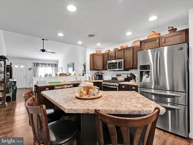 kitchen featuring a kitchen island, a breakfast bar area, dark hardwood / wood-style flooring, kitchen peninsula, and stainless steel appliances