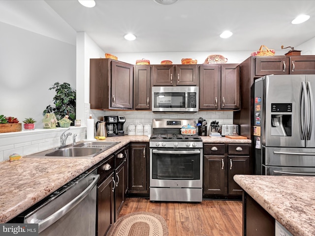 kitchen featuring stainless steel appliances, light hardwood / wood-style floors, sink, and dark brown cabinets