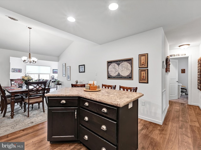 kitchen featuring pendant lighting, lofted ceiling, a kitchen island, dark hardwood / wood-style flooring, and a chandelier