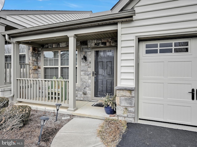 view of exterior entry with a garage and covered porch