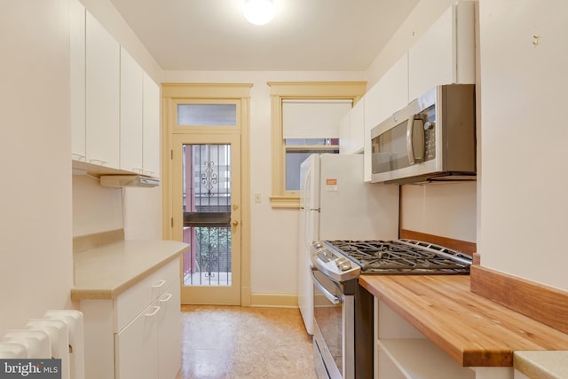 kitchen featuring white cabinetry, appliances with stainless steel finishes, radiator, and butcher block counters