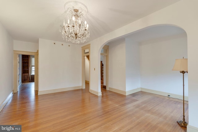 empty room featuring an inviting chandelier and light wood-type flooring