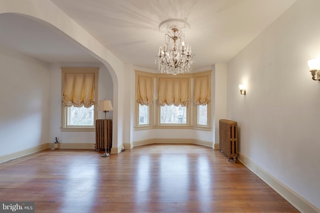 unfurnished room with radiator heating unit, a chandelier, and light hardwood / wood-style flooring