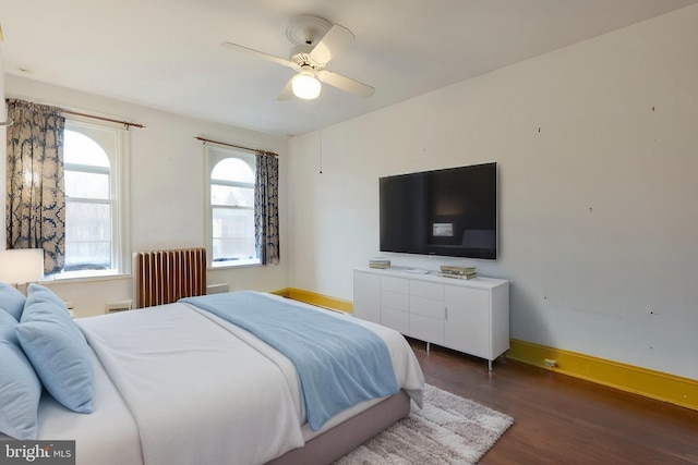 bedroom with ceiling fan, radiator, and dark hardwood / wood-style floors