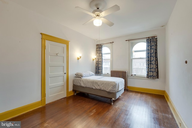 bedroom with ceiling fan, radiator heating unit, and dark hardwood / wood-style flooring