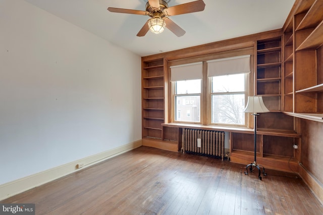 unfurnished office featuring hardwood / wood-style flooring, ceiling fan, and radiator heating unit