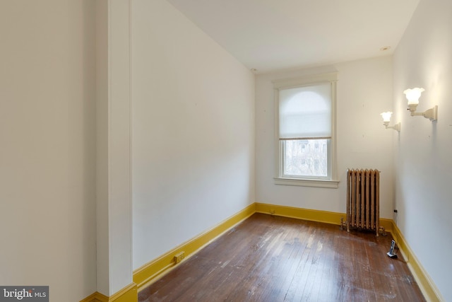 unfurnished room featuring radiator heating unit and dark hardwood / wood-style floors