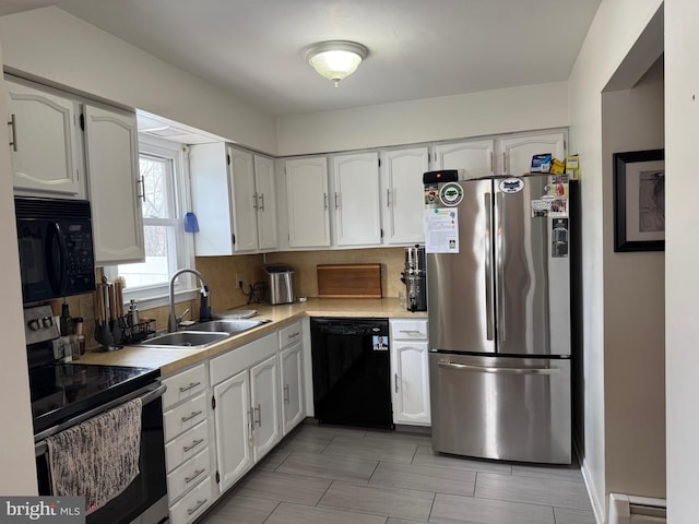 kitchen featuring sink, tasteful backsplash, black appliances, baseboard heating, and white cabinets