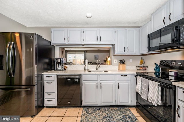 kitchen with light tile patterned flooring, sink, a textured ceiling, and black appliances