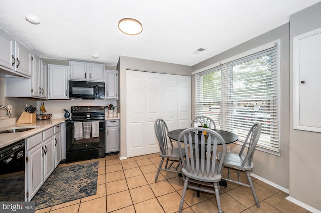 kitchen featuring sink, a textured ceiling, light tile patterned floors, gray cabinets, and black appliances