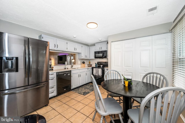 kitchen featuring white cabinetry, light tile patterned flooring, sink, and black appliances