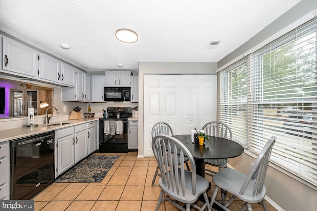 kitchen featuring light tile patterned floors, sink, a textured ceiling, and black appliances