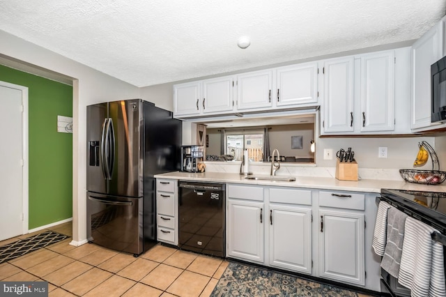 kitchen with white cabinets, light tile patterned floors, sink, and black appliances