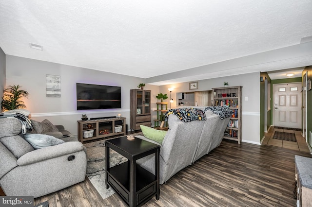 living room with a textured ceiling and dark hardwood / wood-style flooring