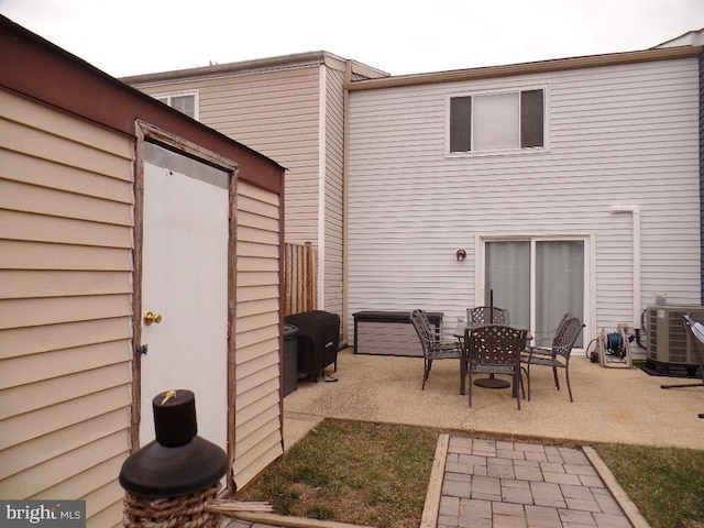 back of property with central AC unit and a patio