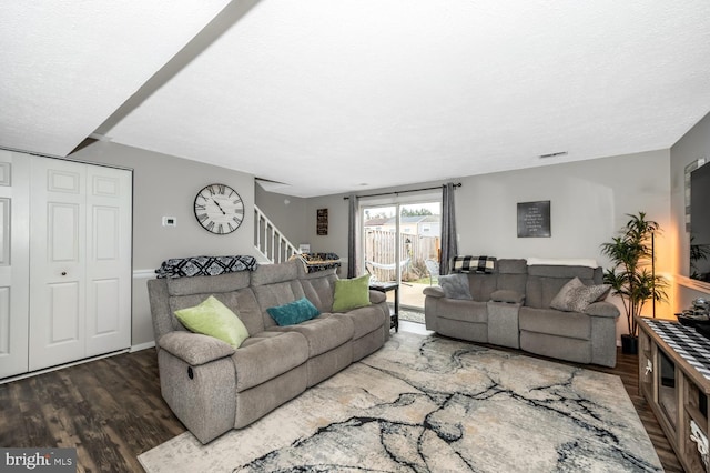 living room featuring dark wood-type flooring and a textured ceiling