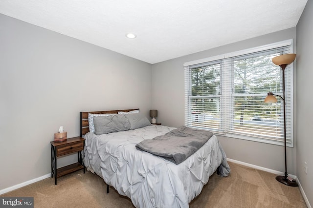 bedroom featuring multiple windows, light carpet, and a textured ceiling