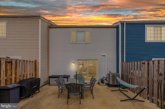 back house at dusk featuring central AC unit and a patio