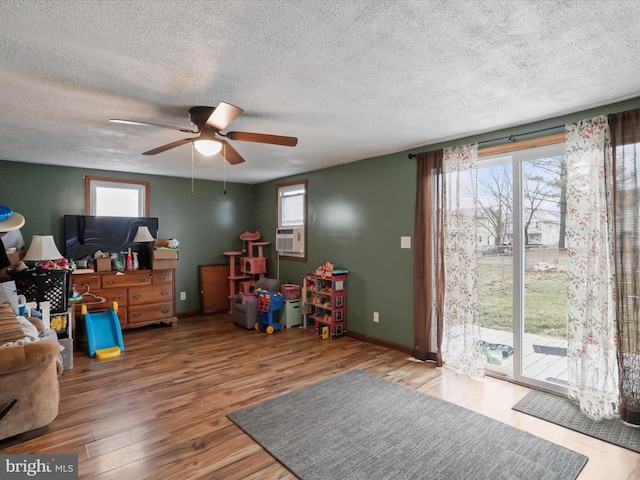 playroom with ceiling fan, a healthy amount of sunlight, wood-type flooring, and cooling unit