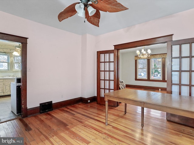 unfurnished office with wood-type flooring and ceiling fan with notable chandelier