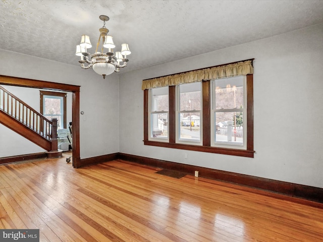 spare room with hardwood / wood-style floors, a notable chandelier, and a textured ceiling