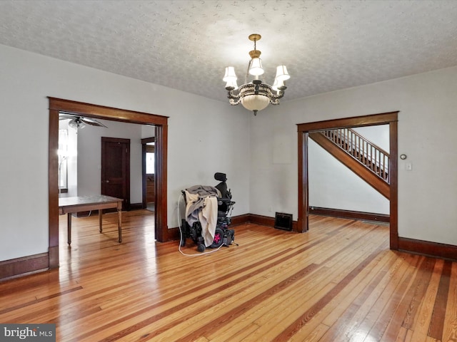 unfurnished room with an inviting chandelier, hardwood / wood-style floors, and a textured ceiling