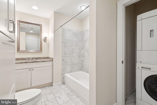 full bathroom featuring tiled shower / bath, stacked washer / dryer, toilet, and vanity