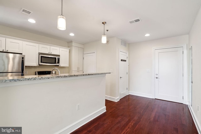 kitchen featuring white cabinetry, stainless steel appliances, hanging light fixtures, and light stone counters