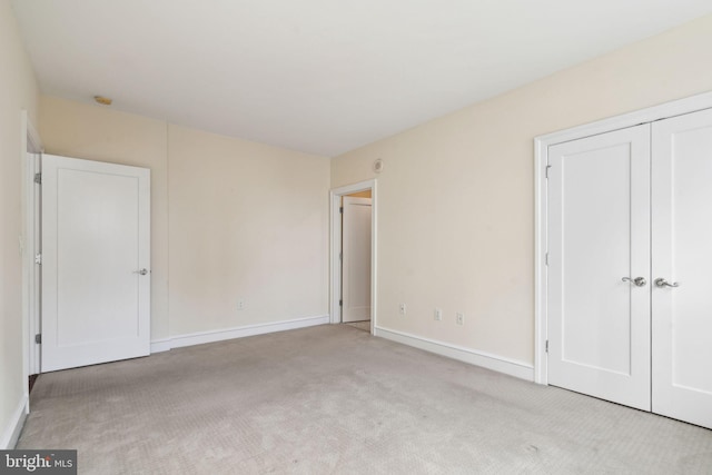 unfurnished bedroom featuring light colored carpet and a closet