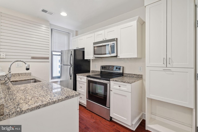 kitchen featuring sink, white cabinetry, stainless steel appliances, light stone countertops, and dark hardwood / wood-style flooring