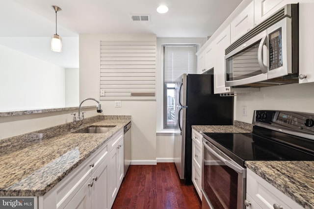 kitchen featuring appliances with stainless steel finishes, sink, white cabinets, and decorative light fixtures