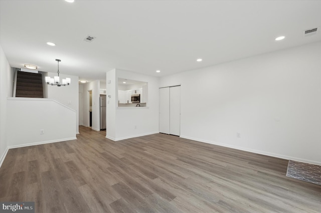 unfurnished living room featuring hardwood / wood-style flooring and an inviting chandelier