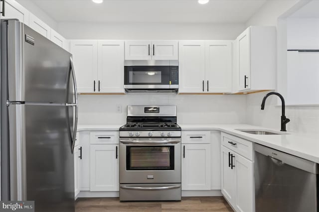 kitchen featuring stainless steel appliances, white cabinetry, and sink