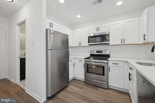 kitchen featuring hardwood / wood-style flooring, stainless steel appliances, and white cabinets