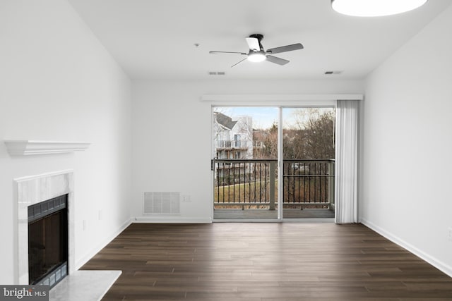 unfurnished living room with dark hardwood / wood-style floors, a premium fireplace, and ceiling fan