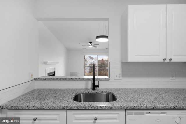 kitchen featuring sink, white cabinetry, tasteful backsplash, light stone counters, and dishwashing machine