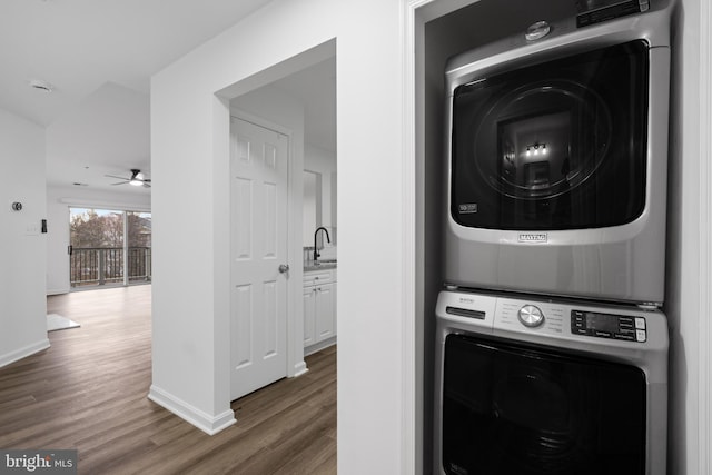 laundry area featuring dark hardwood / wood-style flooring, sink, and stacked washer and clothes dryer